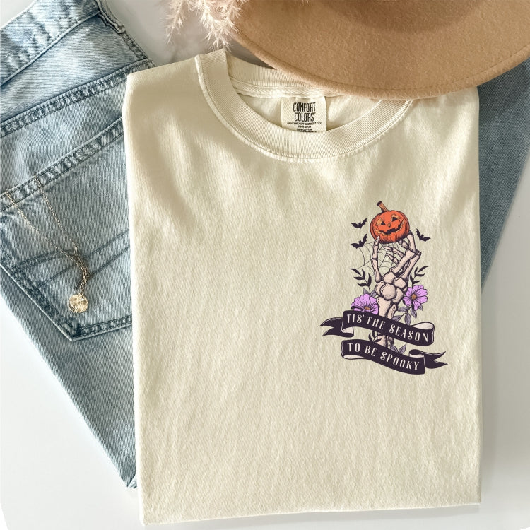 "Tis the Season to be Spooky" Skeleton Hand with Flowers and Pumpkins Pocket Design Tee